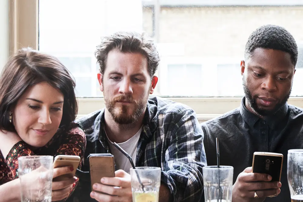 Three young adults on cell phones